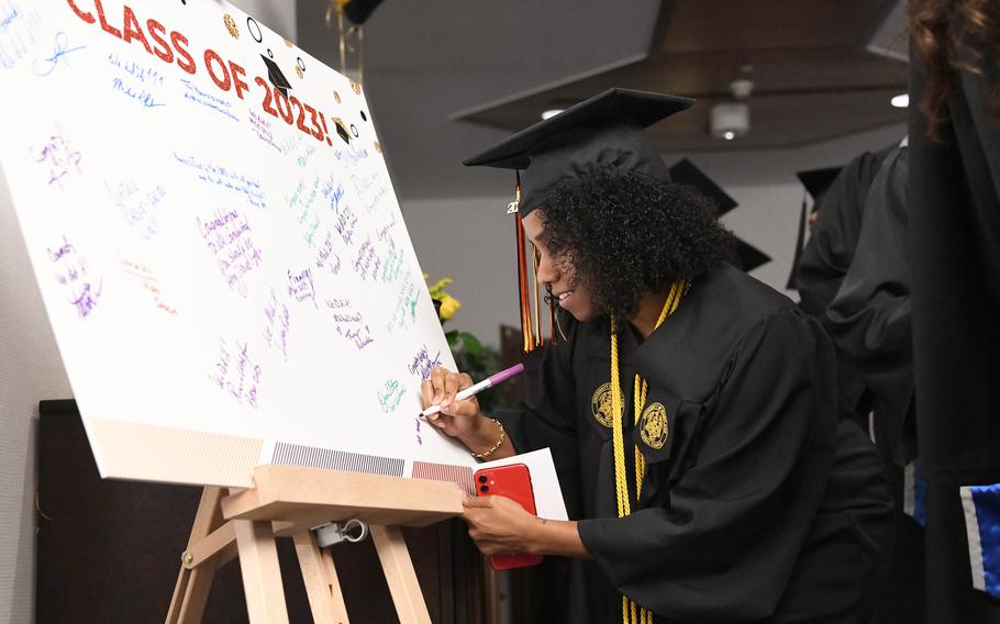 Civilian Rashonda Gumbs signs a board for 2023 graduates of the University of Maryland Global Campus Europe, Saturday, April 29, 2023.