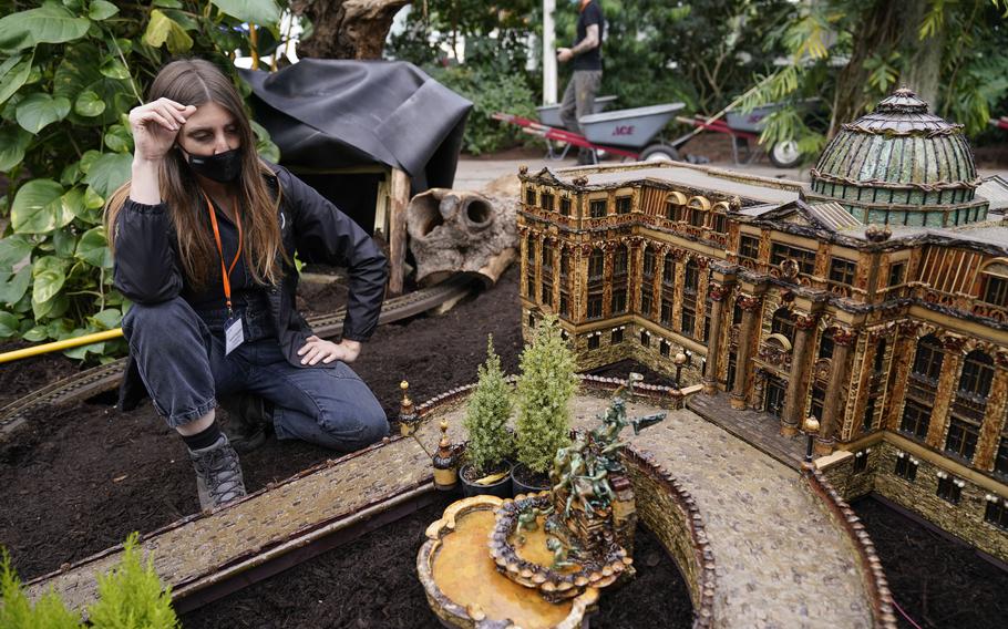 Laura Busse Dolan looks over the newest creation in the Holiday Train Show, a miniature of the LuEsther T. Mertz Library, at the New York Botanical Garden in New York, Thursday, Nov. 11, 2021. The show, which opens to the public next weekend, features model trains running through and around New York landmarks, recreated in miniature with natural materials.