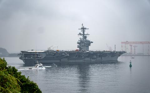 An aircraft carrier sails in a bay.