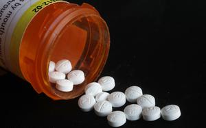 Pills spill out of a bottle in an arrangement photo of prescription Oxycodone.