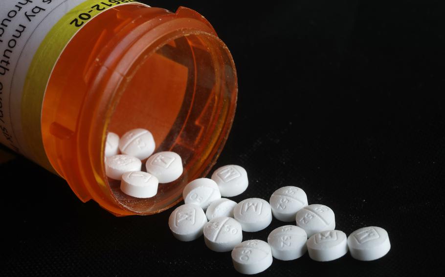 Pills spill out of a bottle in an arrangement photo of prescription Oxycodone.