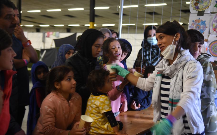 Madina Fahim, 15, hands out cups of tea and formula at Rhine Ordnance Barracks, Germany, on Sept. 20, 2021. Fahim, whose family fled Afghanistan last month, practices her English while helping American volunteers take requests for formula and tea at the temporary living area for evacuees at ROB. She is eager to go to the United States, where she wants to study medicine.