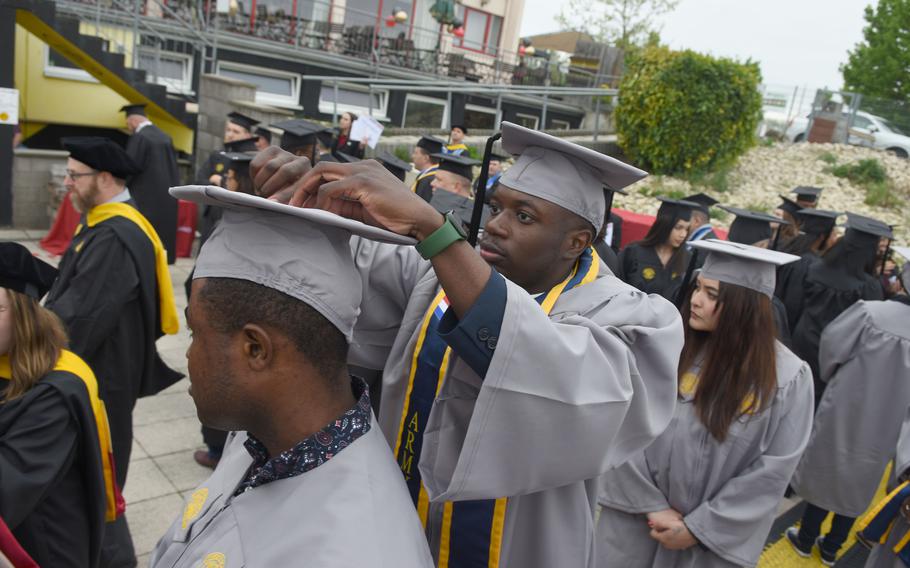Army Spc. Ali Camara helps Spc. Samuel Omojola adjust his graduation cap before the commencement ceremony on Saturday, April 30, 2022, for the University of Maryland Global Campus Europe class of 2022. Camara and Omojola received associate’s degrees while assigned to Rhine Ordnance Barracks in Kaiserslautern, Germany.