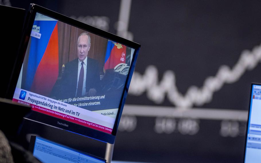 Russia’s President Vladimir Putin appears on a television screen at the stock market in Frankfurt, Germany, Feb. 25, 2022. Russia is revving up its sophisticated propaganda machine as its military advances in neighboring Ukraine. Analysts who monitor propaganda and disinformation say they’ve seen a sharp increase in online activity linked to the Russian state in recent weeks. 