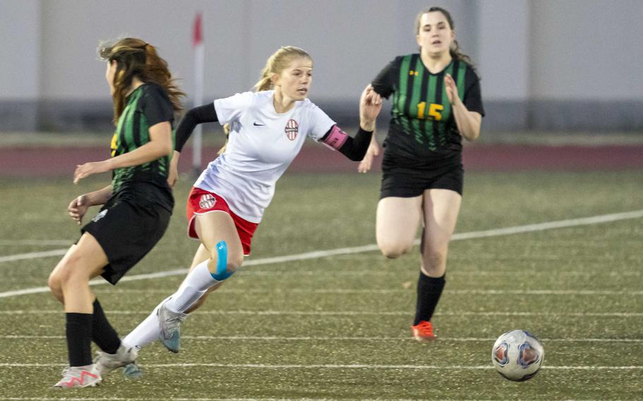 Nile C. Kinnick’s Bree Withers cuts toward the ball between Robert D. Edgren’s Saige Whitmore and Dann Waldo during Friday’s DODEA-Japan girls soccer match. The Red Devils won 10-0.