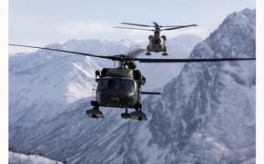 An Alaska Army National Guard UH-60L Black Hawk helicopter, foreground, and a CH-47F Chinook helicopter, fly between the Chugach Mountains during sling-load training near Joint Base Elmendorf-Richardson, Alaska, Feb. 28, 2024. U.S. Army Soldiers from the Alaska Army National Guard Aviation Battalion conducted the sling-loaded training to enhance their ability to operate in Alaska’s harsh environment. (Alaska National Guard photo by Alejandro Peña)