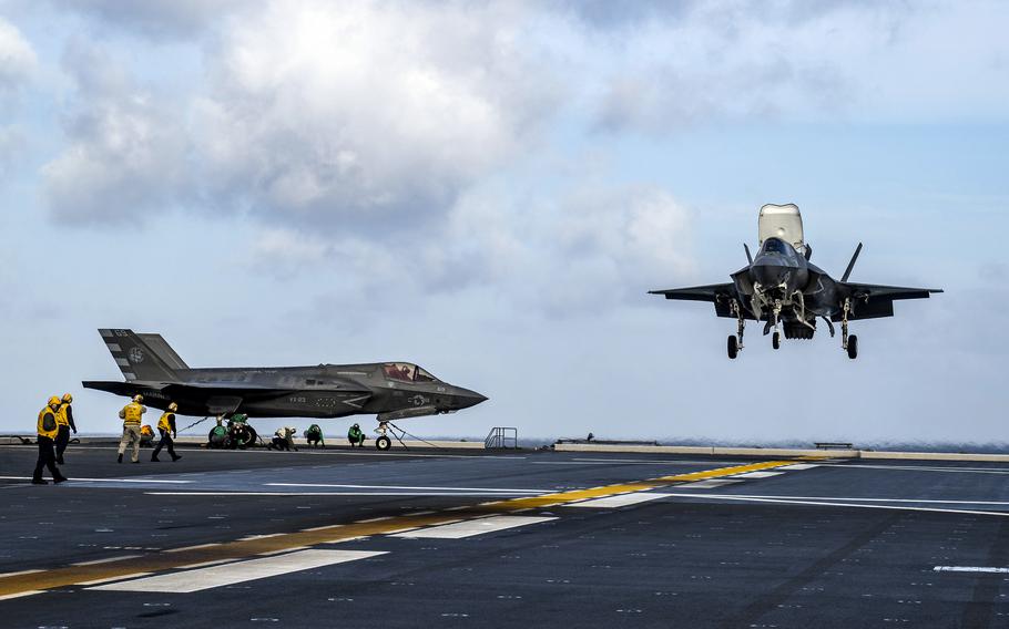 A crew on the deck of JS Kaga watches as a F-35 B lands.