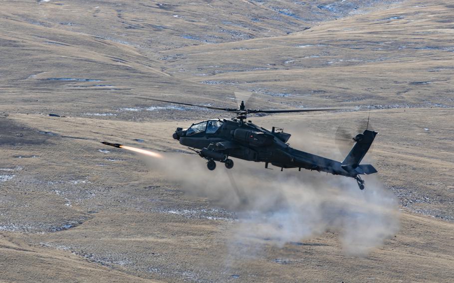 An AH-64E Apache helicopter fires an AGM-114 Hellfire missile.
