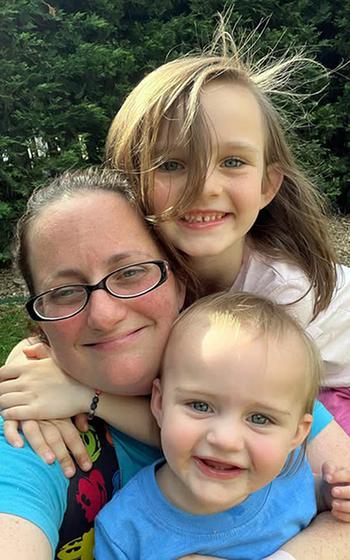 Jordan Anders gets a hug from her daughter while holding her son.