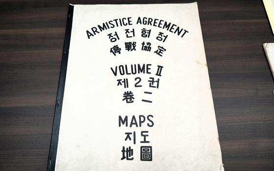 A large booklet that says “Armistice Agreement Maps Volume II” on the cover in black lettering and translated into Chinese and Korean.