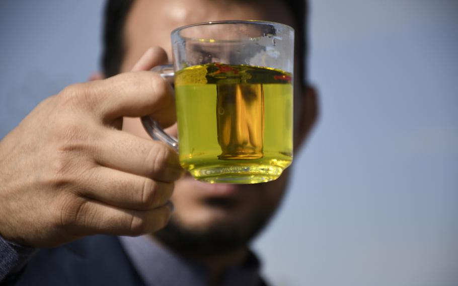 An agricultural specialist who manages a saffron processing plant holds up a glass of saffron tea while traveling to a village in a rural district of Herat province in Afghanistan.  