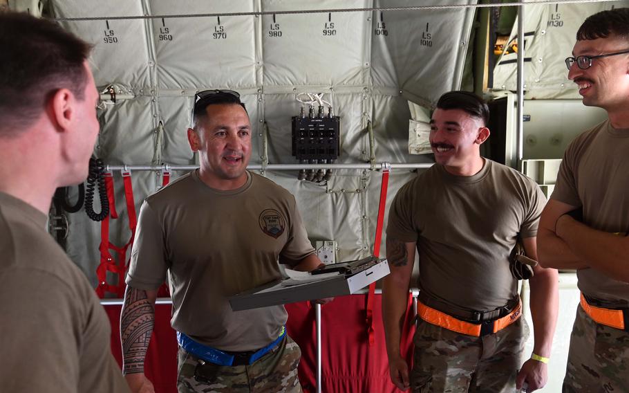 Master Sgt. Ramon Mestas, 2nd from left, a judge at the Port Dawg Rodeo at Ramstein Air Base, Germany, July 6, 2022, talks to the 8th Expeditionary Air Mobility Squadron team from Al Udeid Air Base, Qatar, after they loaded and tied down a Humvee on a C-130 Hercules aircraft.