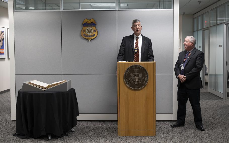Stupar stands at the microphone, and Yockelson stand to his left. The long book is on a table to Stupar’s right.