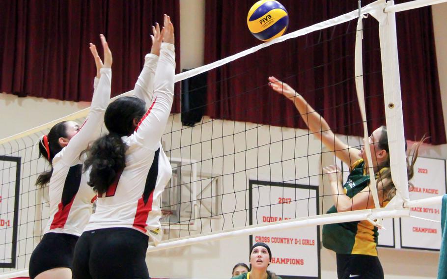Edgren's Kaiya Pasion spikes against Kinnick's Isabella Marchetti and Jordan Kitts.