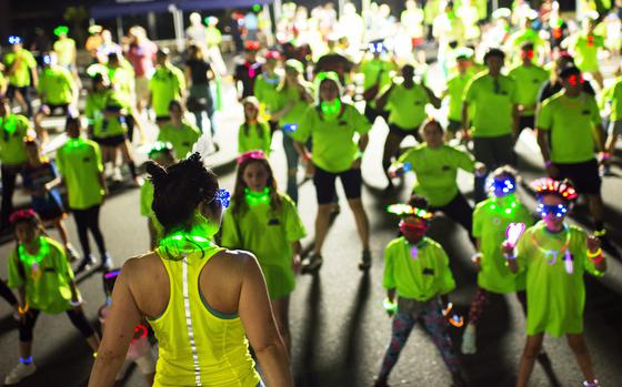 Runners warm up with a Zumba session ahead of a neon fun run at Atago Sports Complex in Iwakuni city, Japan, Saturday, June 24, 2023. 