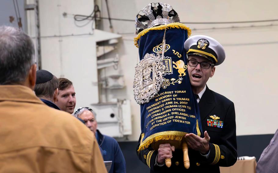 Lt. Cmdr. Yonatan Warren, a Jewish chaplain assigned to the  aircraft carrier USS Harry S. Truman, carries the Torah during the dedication and reinstallation ceremony for it on the ship at Naval Station Norfolk, Va., March 2, 2024.  It was first dedicated to the ship in 2007. Truman and at least one other Navy aircraft carrier have Holocaust-surviving Torahs.  