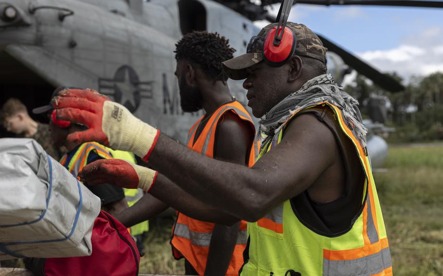 An aid worker worker grabs supplies to load onto a CH-53E Super Stallion during a humanitarian assistance and disaster relief operation on Bougainville Island, Papua New Guinea, Aug. 12, 2023.