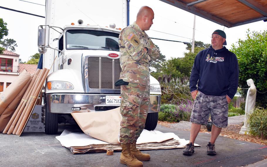 Col. Varman Chhoeung, commander of U.S. Army Garrison Presidio in Monterey, Calif., speaks with Zane Whetstone, who is moving to Japan with his family, as movers pack up his household goods in Pebble Beach, Calif., July 16, 2021.