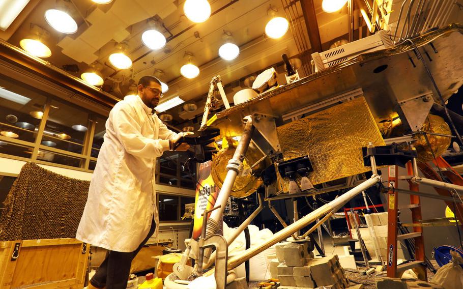 Pasadena, California -Dec. 7, 2022-Pranay Mishra, a systems engineer for NASA’s Jet Propulsion Laboratory, next to ForeSight, a model of NASA’s Mars InSight satellite, Dec. 7, 2022. NASA’s Mars InSight mission will likely end in January when dust covers the lander’s solar panels and it stops transmitting data. ForeSight has been put through all kinds of trials at JPL, and engineers are packing it up next week and putting it in storage now that the mission is expected to end.