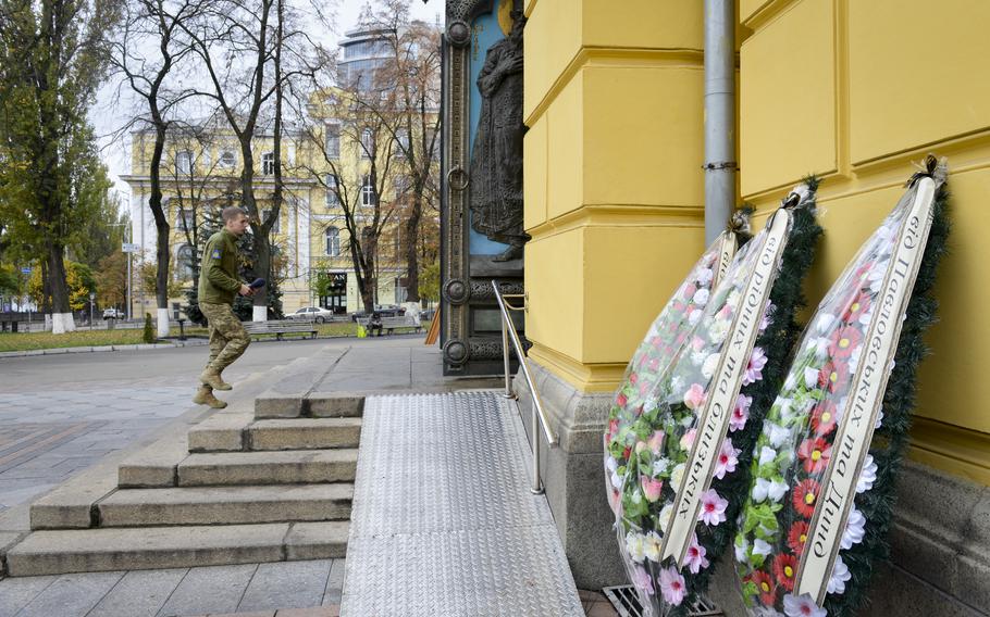 A Ukrainian soldier walks past flower memorials to war dead into St. Volodymyr's Cathedral, a major center for the Orthodox Christian community in Kyiv, Ukraine, on Oct. 26, 2022.