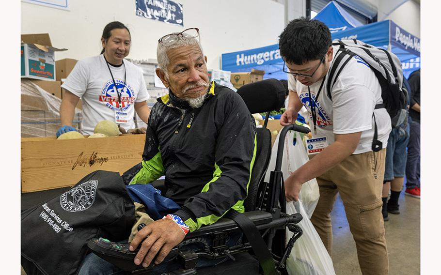 Kim Yee, a homeless Vietnam War veteran, gets bags of fresh produce from Joe Pham, left, and Raiki Omori at the Veterans Stand Down event at the Santa Clara County Fairgrounds in San Jose, Calif., Saturday, July 8, 2023. The two-day event continues Sunday. 