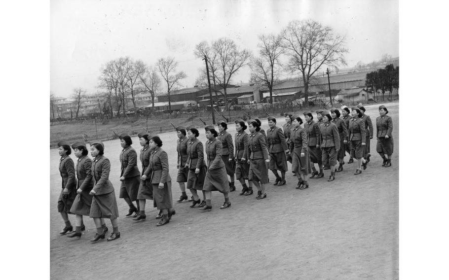 WACs march in formation at the WAC Training Center in Seoul. The recruits, all of whom have completed at least high school, receive 20 weeks of training in clerical work or communications before they are sent out as privates first class to units. Their training courses included the use of weapons as well as sewing and home economy.