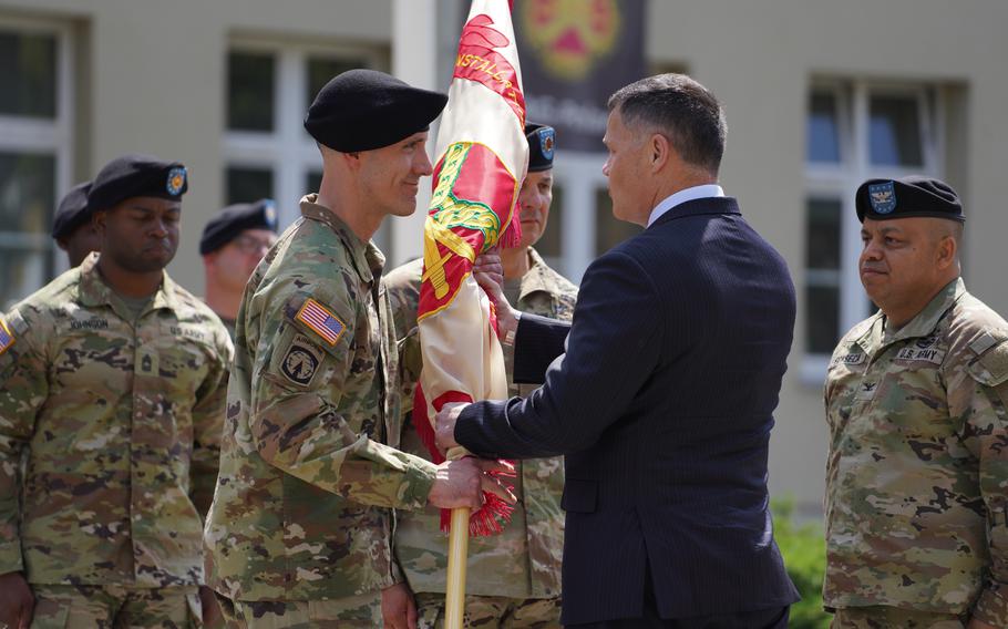 Col. Christopher Church receives the U.S. Army Garrison Poland colors from Tommy Mize during a ceremony at Camp Kosciuszko in Poznan, Poland, on June 26, 2023. Church replaced Col. Jorge Fonseca, right, as garrison commander.