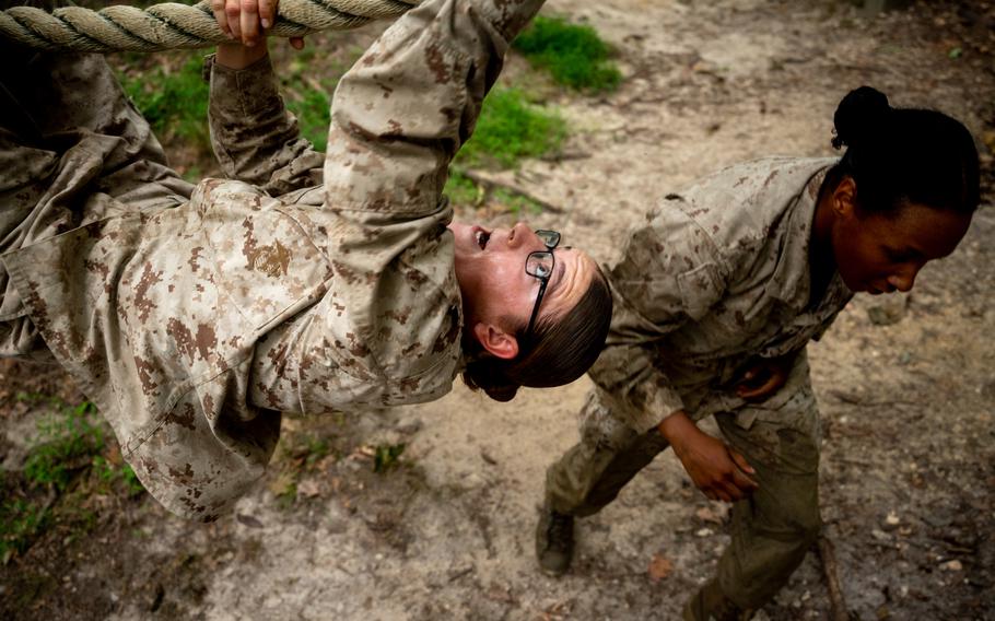 A Marine climbs a rope and another runs.
