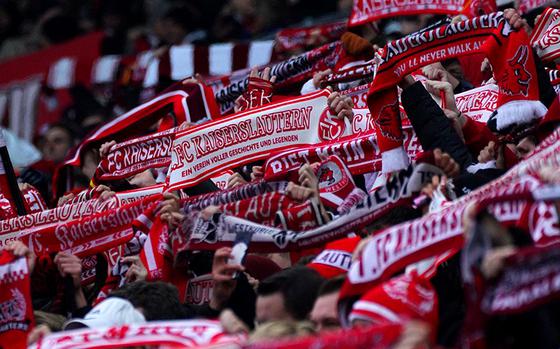 1. FC Kaiserslautern fans hold up their red and white team scarves.