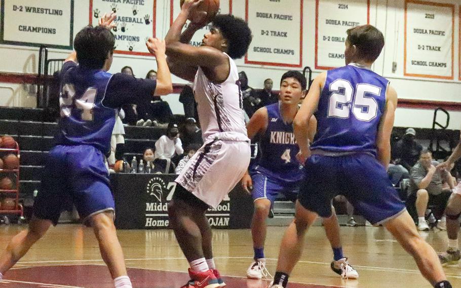 Zama's Amari King tries to shoot while surrounded by Christian Academy Japan defenders during Monday's Kanto Plain boys basketball game. The Trojans won 57-33.
