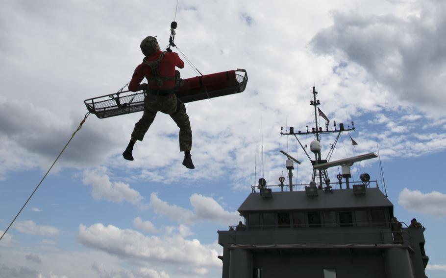 An Air Force pararescue specialist and a simulated casualty are lifted by a Pave Hawk helicopter from an Army landing craft off Okinawa, Japan, on Nov. 10, 2021.