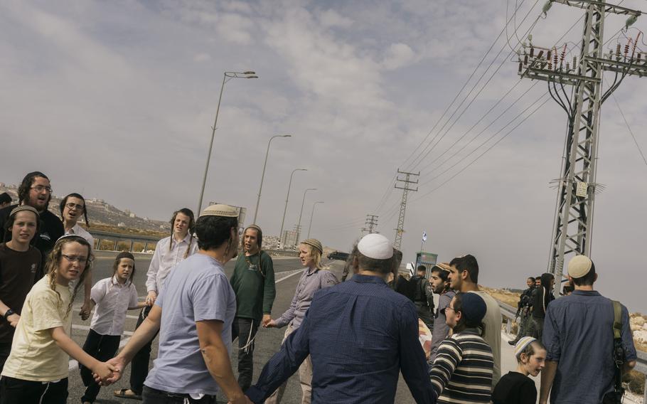 Settlers from Kochav Hashachar pray on the road to the Palestinian village of Taybeh on Friday.