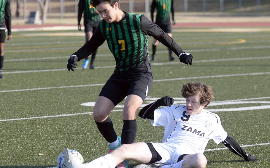 Zama's Tyler Deiwert slide tackles the ball away from Robert D. Edgren's Axel Noguera during Friday's DODEA-Japan soccer match. The Trojans won 2-0.