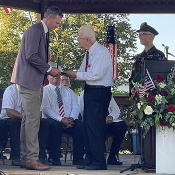 A man receives a medal from another man during a ceremony.