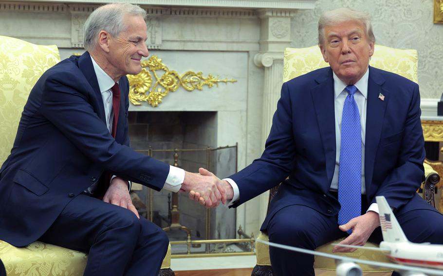 The leader of Norway, left, shakes hand with Donald Trump. Both are in blue suits.