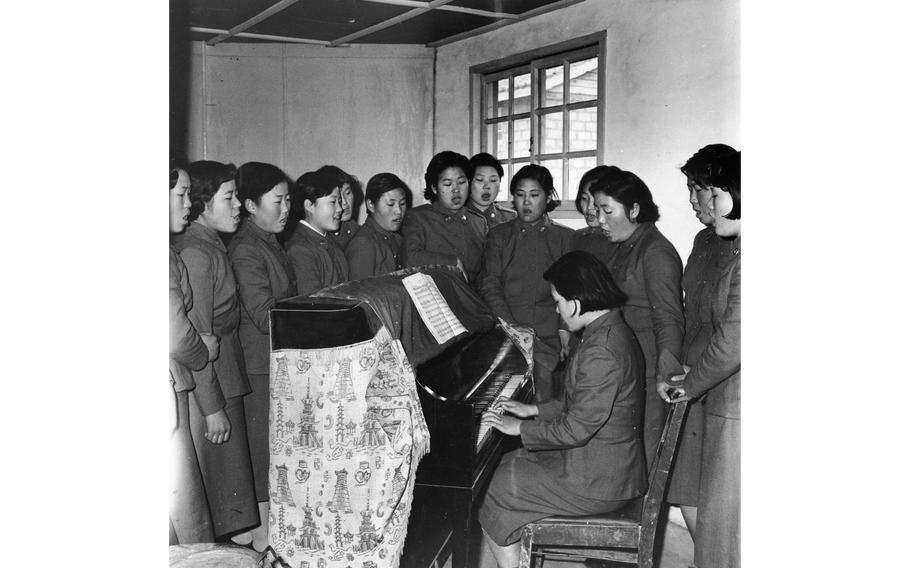 A young Republic of Korea Women’s Army Corps recruit plays the piano as her fellow trainees sing in the dayroom at the WAC Training Center in Seoul. 