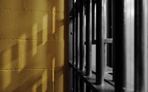 A corner of a prison cell with yellow cinderblocks.