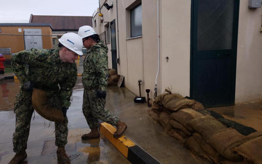 Seaman Apprentices Ian Hooper and Ashley Gustaveson place sandbags Oct. 26, 2021, at a wastewater plant at Naval Air Station Sigonella, Italy.