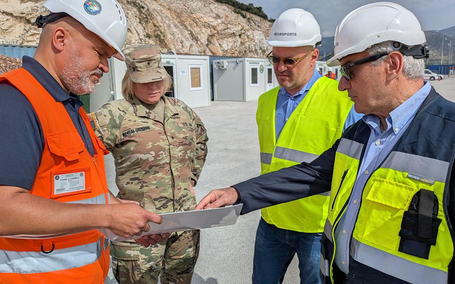 Gen. Monday-Gresham listens as three men point out information on a piece of paper.