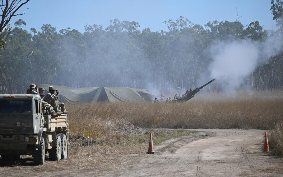 The air is hazy as Marines fire an M77 howitzer.