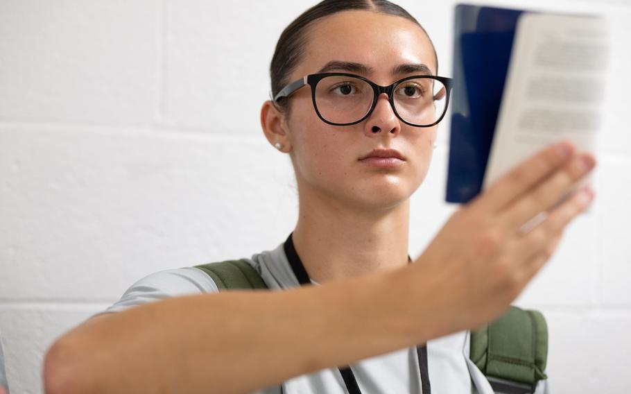 A Coast Guard Academy cadet reads a small book