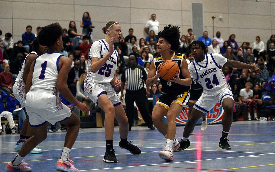 Stuttgart’s Ismael Anglada-Paz picks up the ball in the lane midst three Royal defenders – from left, Christian Roy, Kelan Vaugh, and Leon Pierre-Louise – during a basketball game on Dec. 8, 2023, at Ramstein High School on Ramstein Air Base, Germany.