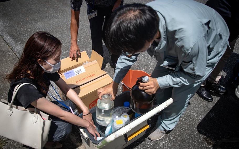 Japanese officials collect samples of treated wastewater at Marine Corps Air Station Futenma, Okinawa, July 19, 2021. 