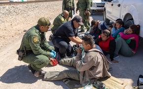 U.S. Border Patrol agents render medical aid to migrants traveling with a group that crossed the border near Sunland Park, New Mexico, on March 19, 2019. Two brothers in Texas have been arrested after authorities say one of them opened fire on a group of migrants getting water near the U.S.-Mexico border.