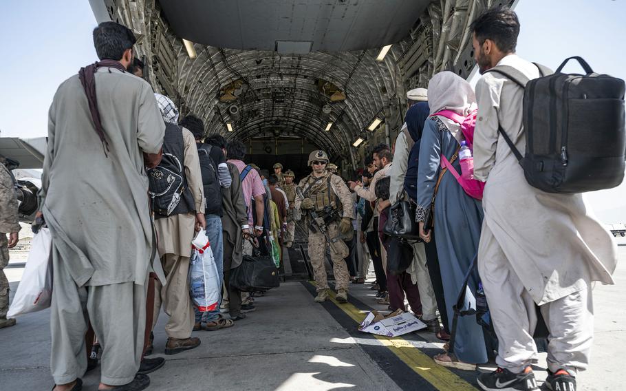 Des aviateurs et des Marines américains guident des évacués à bord d'un C-17 Globemaster III à l'aéroport international Hamid Karzai de Kaboul, Afghanistan, le 21 août 2021. 