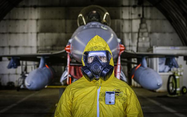 Tech. Sgt. Kayla Bradford waits for a radiological assessment on an F-16 Fighting Falcon during exercise Radiant Falcon, held April 24, 2024, at Spangdahlem Air Base, Germany. She is wearing a device that monitors gamma and beta radiation exposure in real time and alerts the user to unsafe exposure levels.