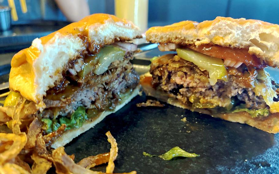 A cheeseburger with fried onions, jalapenos and barbecue sauce.