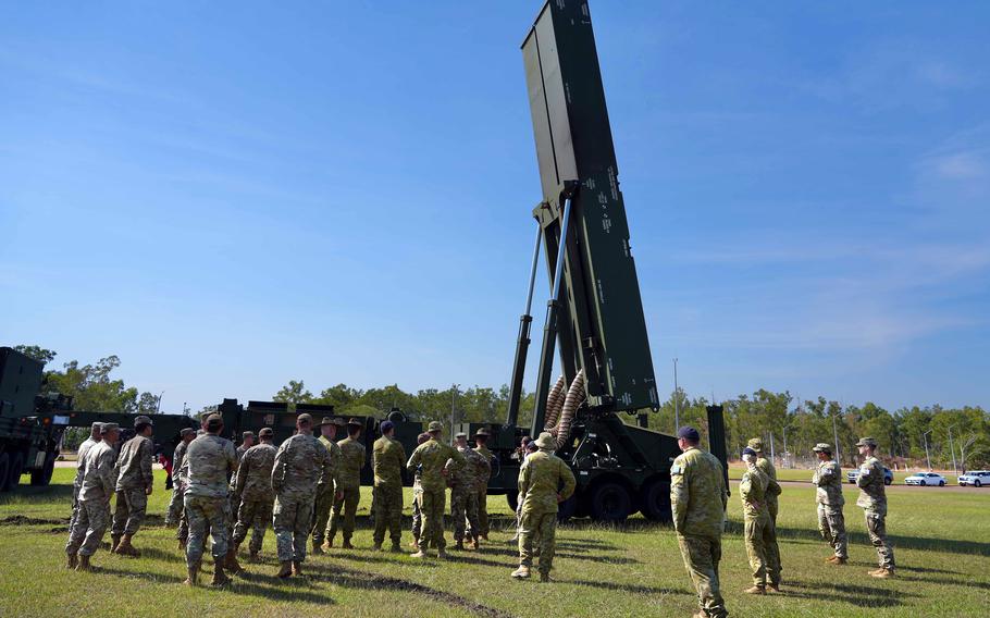 Dozens of service members stand in front of the Dark Eagle hypersonic missile system with a blue sky in the background.