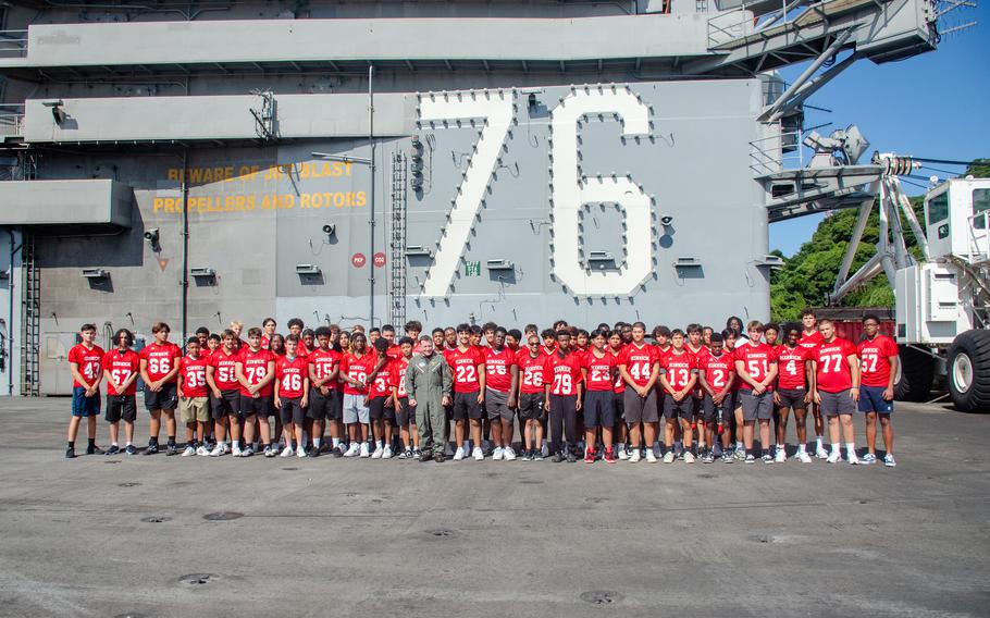Members of the Nile C. Kinnick High School football team pose with Capt. Daryle Cardone, commander of the USS Ronald Reagan, aboard the carrier at Yokosuka Naval Base, Japan, Tuesday, Sept. 12, 2023.