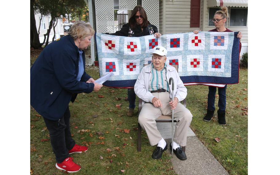 Sue Simmons, left, vice president of Blue Star Mothers and a volunteer with Quilts of Valor, presents WWII veteran Denver Conard with a quilt on Oct. 22, 2021. Conard recently recently turned 100. Holding the quilt in the background are Thea Dryden and Shannon Kuhn.